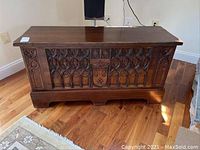 Front view of the wood chest showing carved panels and flat top surface