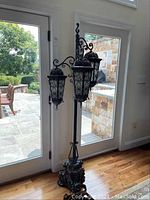 Full view of the wrought iron floor lamp in front of glass doors