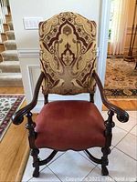 Full front view of chair showing wood frame, patterned fabric backrest, red leather seat, turned legs and arms