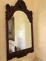 Full view of the large wall mirror with the ornate dark wooden frame and beveled glass.