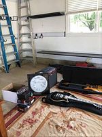 Overview of two guitars (one in soft case, one in gig bag), amp, microphones in box and signed drum head