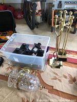 Brass fireplace tool set with 4 tools and stand, Waterford foyer chandelier, and plastic bin with nine outdoor tea lamps