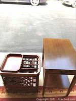 Photo showing wooden magazine rack with detailed panel sides and sliding tray alongside a plain wooden single drawer end table.