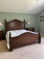 Full assembly of carved wood bed frame with headboard, footboard and side rails installed on box springs