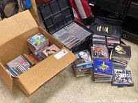 Overview photo of boxes and stacks of CDs and DVDs, some visible titles include Shrek 2, Tina Turner, and Frank Sinatra.
