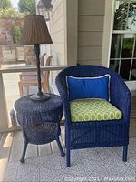 Photo showing blue wicker chair, blue wicker round table, and black lamp with wicker lampshade on top