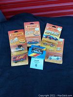 Six Matchbox vehicles in original packaging displayed on black fabric, showing front view of all cards and vehicles.