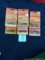 Six vintage Matchbox die-cast vehicles in original blister packaging laid in two rows on dark fabric.