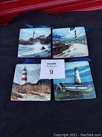 Four square ceramic lighthouse wall plates each with a blue ribbon for hanging. Plates are arranged on a dark surface showing colorful coastal lighthouse scenes with ocean and dunes.