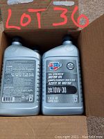 Open cardboard box containing six 1-quart bottles of Carquest full synthetic 10W-30 motor oil. Two bottles visible fully, with clear labels showing brand and viscosity.