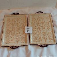 Set of two rectangular serving/baking trays with orange floral lace pattern and brown handles on white background