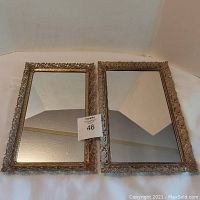 Two rectangular vintage mirrored vanity trays with ornate metal frames side by side on white background.