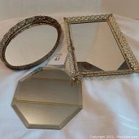 Full view of all three mirrors: oval with ornate metal frame, rectangular with raised floral frame and mirror damage, and octagonal beveled frameless mirror.