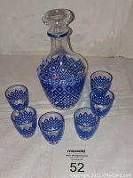 Full set arranged with the decanter centered and six shot glasses placed around it, showing blue diamond decorative pattern.