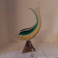 Side view of Murano glass fish figurine showing blue and yellow coloration and curved shape.