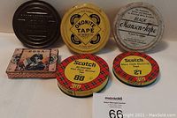 Full top view of six vintage advertising tins arranged in two rows. Shows Chase and Sanborn embossed black tin, Okonite Tape yellow tin, Black Manson Tape white tin, Rosa Cigarillo rectangular tin, Scotch 88 and Scotch 27 electrical tape tins with red plaid lids.