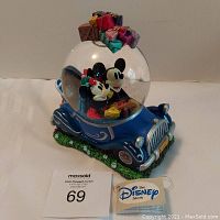 Front and angled view of the Disney musical snowglobe showing Mickey and Minnie driving a blue car with wrapped gifts on top.
