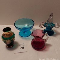 Front view of four vintage art glass items including green vase, blue open compote, cranberry swirl creamer, and turquoise basket with handles