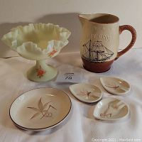 Photo shows the green satin custard glass compote with hand-painted roses on pedestal, Navy Grog ceramic pitcher with embossed ship and rope handle, one round plate, and three small ashtrays arranged on cloth.