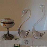 Full view of vintage pedestal candy/trinket box, two clear glass swan figurines of differing sizes, and small rectangular crystal paperweight
