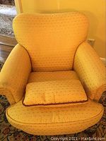 Front view of yellow upholstered club chair with matching pillow on seat