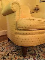Close up of yellow upholstered chair arm and side cushion showing upholstery pattern and fabric texture.