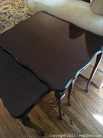 Photo of largest and medium nesting tables stacked showing scalloped edges and dark wood finish.