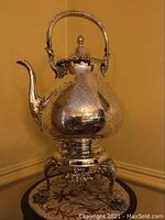 Full front view of silver-plated kettle on stand showing overall form and finish