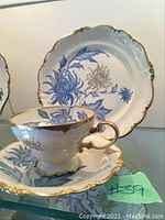 Photo showing tea cup, saucer, and plate with blue floral pattern and gold trim