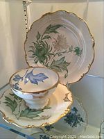 Photo showing the decorative plate, one tea cup with blue floral design and gold trim, and saucer with gold trim and green floral design.