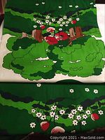 Close-up photo of the textile fabric spread out, showing its bold Scandinavian floral and fruit design in green, white, and red colors.
