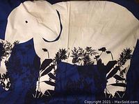 Close-up photo showing white elephant and black botanical designs on blue background textile fabric