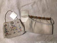 Two vintage beaded purses with a small rectangular mirror laid on a fabric surface.