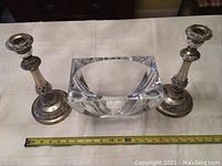 Photo showing set of two silver candle holders and one clear glass vase with measuring tape indicating size.