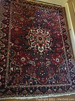Full view of rectangular rug showing red field with central star medallion and patterned border
