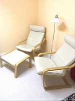 Two lounge chairs and ottoman arranged with floor lamp against peach wall