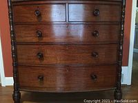 Full front view of bow-front chest showing five drawers, gadroon top trim, turned stiles and bun feet