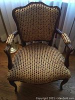 Front view of chair showing carved wood frame and patterned upholstery