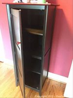 Front view of tall black cabinet with red wood top and single door closed