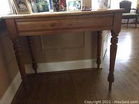 Front view of the rectangular yellowwood table showing the top and front apron with four turned legs.