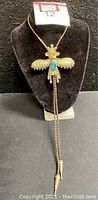 Full view of the gold colored Kachina Dancer Warrior bolo tie displayed on black velvet stand, showing full length and pendant.