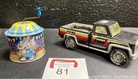 Photo showing black metal Buddy L truck and colorful vintage German wind-up musical toy.
