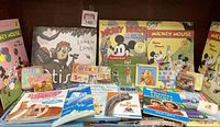Front view of a collection of children's books including Mickey Mouse titles, educational books, and storybooks featuring animals and dinosaurs.
