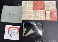 Image of the Ronson soft cloth holder, instruction pamphlet with detailed text and graphics, and the cigarette case with black mirror finish and metal details.