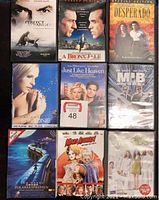 Nine DVDs visible showing titles such as Perfect Stranger, Bronx Tale, Desperado, Simone, Just Like Heaven, Men in Black, Polar Express, Mad About Mambo, and 50 Odd Days. Some discs are in cases with minor wear, others appear sealed.