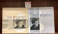 Photo showing two Paul McCartney vinyl albums side by side with different color covers and song listings.