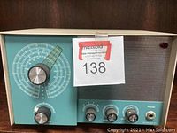 Front view of the vintage electronic device showing the large tuning dial, control knobs, headphone jack, and speaker grille.