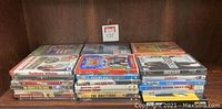 Photo of 30 assorted DVDs laid flat in three stacks showing various movie titles and cover art.