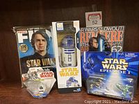 Front view showing the Total Film 100th issue collector's Star Wars magazine with Anakin Skywalker on the cover, Star Wars Revealer magazine, boxed Hasbro R2-D2 figure, Episode I vehicle collection blister pack, and Star Wars micro machine figure.