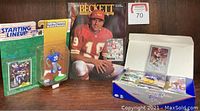 Lot showing Starting Lineup figure and card, Beckett magazine, box of football cards opened with some loose cards, including one prominent card in plastic stand.
